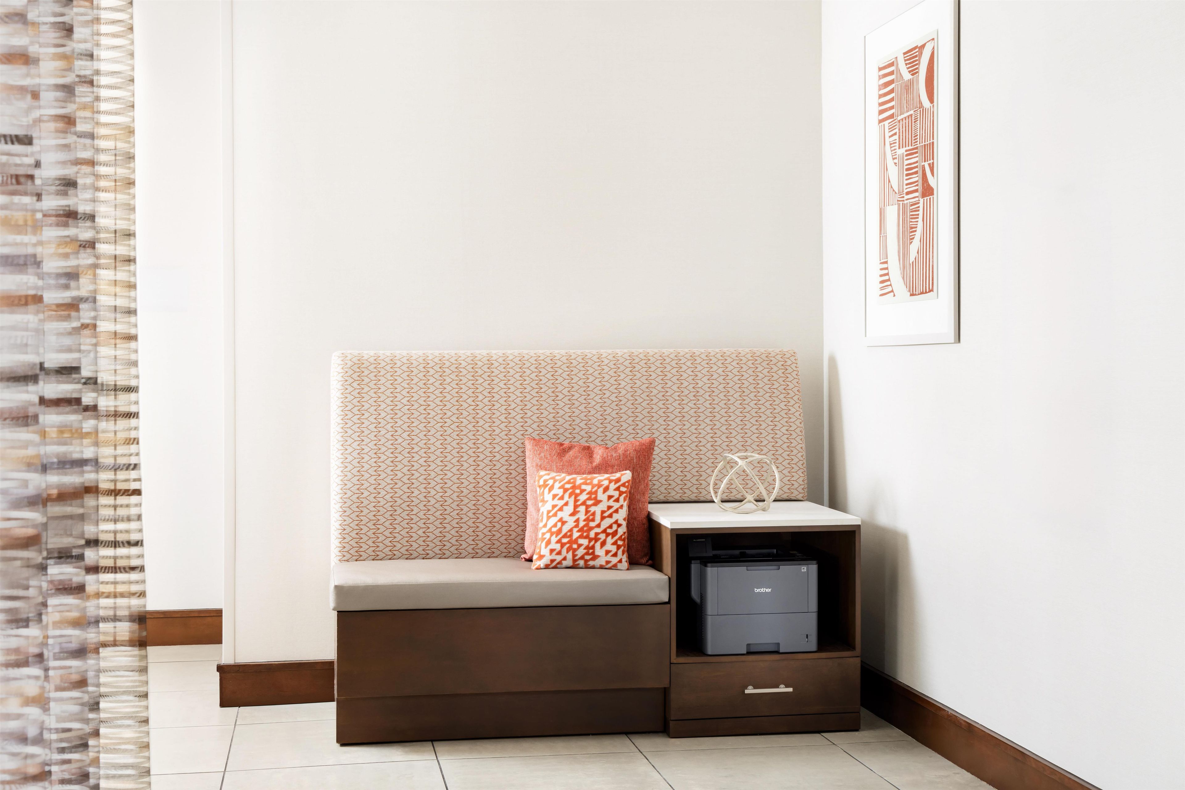 A corner room with a sofa, a small table with a printer, and a patterned wall.