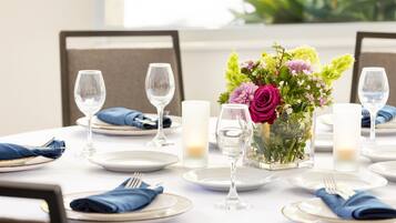 A dining table set for a meal with plates, cutlery, glasses, and a centerpiece of flowers.