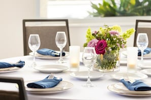 A dining table set for a meal with plates, cutlery, glasses, and a centerpiece of flowers. - Hilton Garden Inn Palo Alto (Palo Alto)
