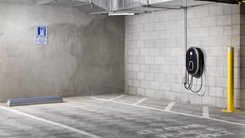 A parking garage with concrete walls, a no parking sign, and electric vehicle charging stations.