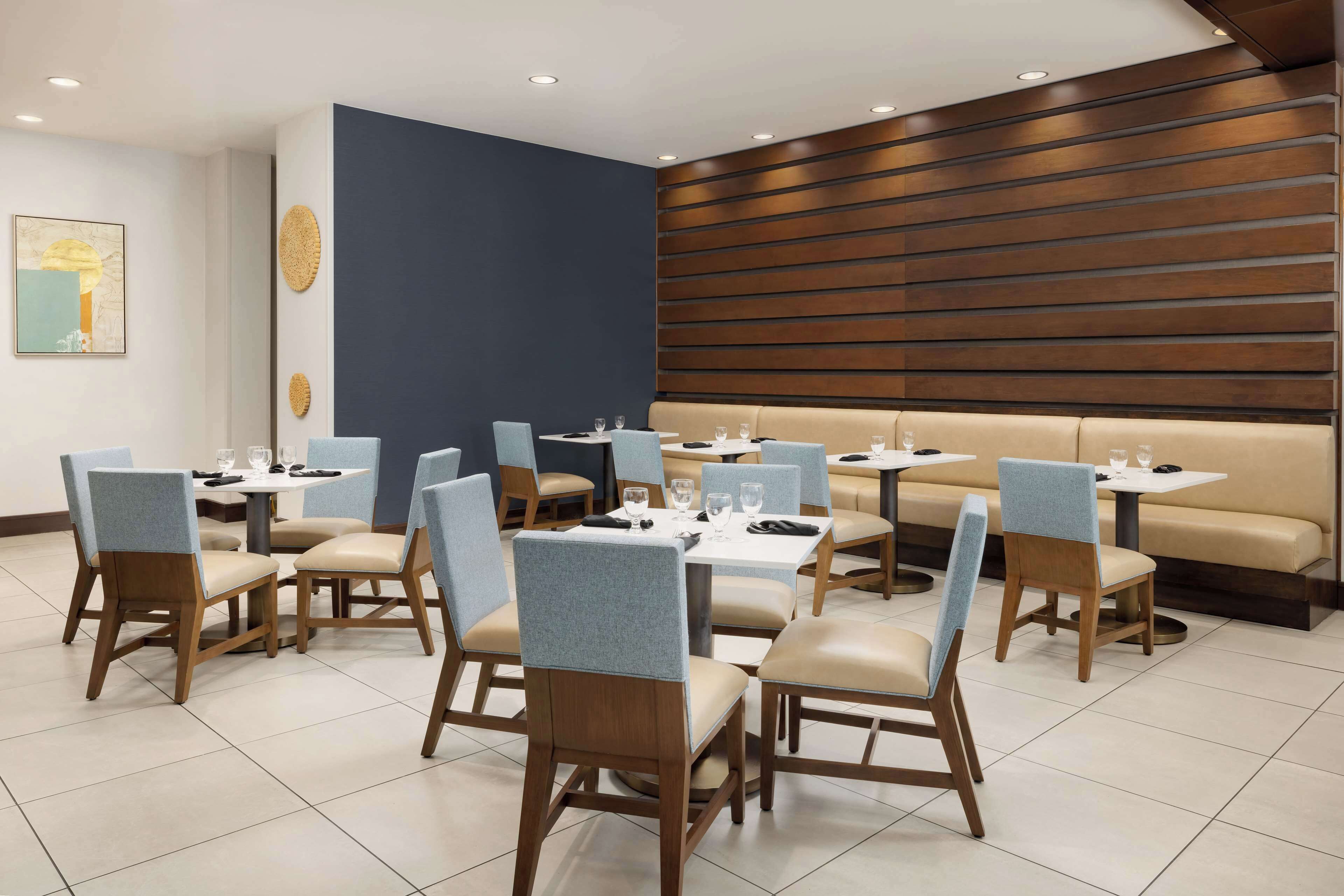 Un restaurante con cabinas y mesas, sillas de madera y una pared de acento azul.