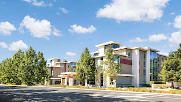 A modern hotel with a clear sky and trees in front.