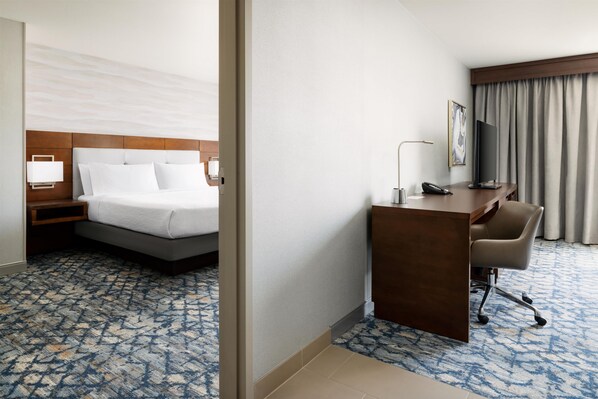 Una habitación de hotel con cama, escritorio, silla y televisor.