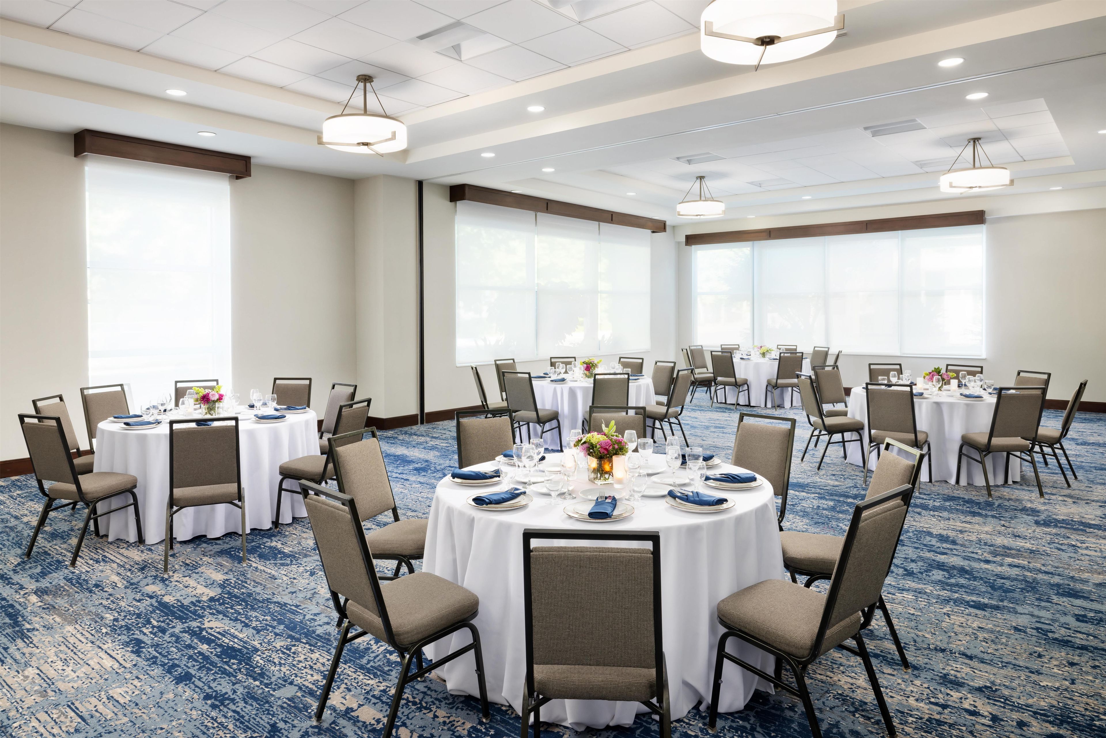 A conference room with round tables, chairs, and a carpeted floor.