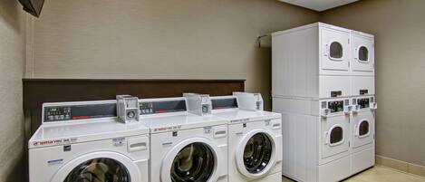 A laundry facility with multiple front-loading washing machines and a stacked dryer unit.