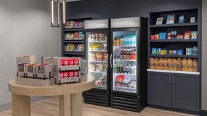 A modern grocery store with refrigerated sections labeled 'COLDER' and shelves stocked with various products.