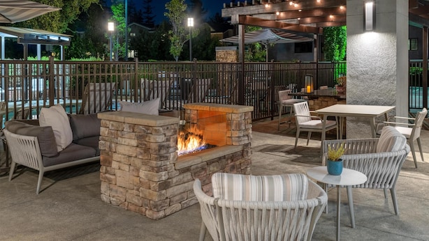 An outdoor patio area with a stone fire pit, wicker furniture, and a table with chairs.