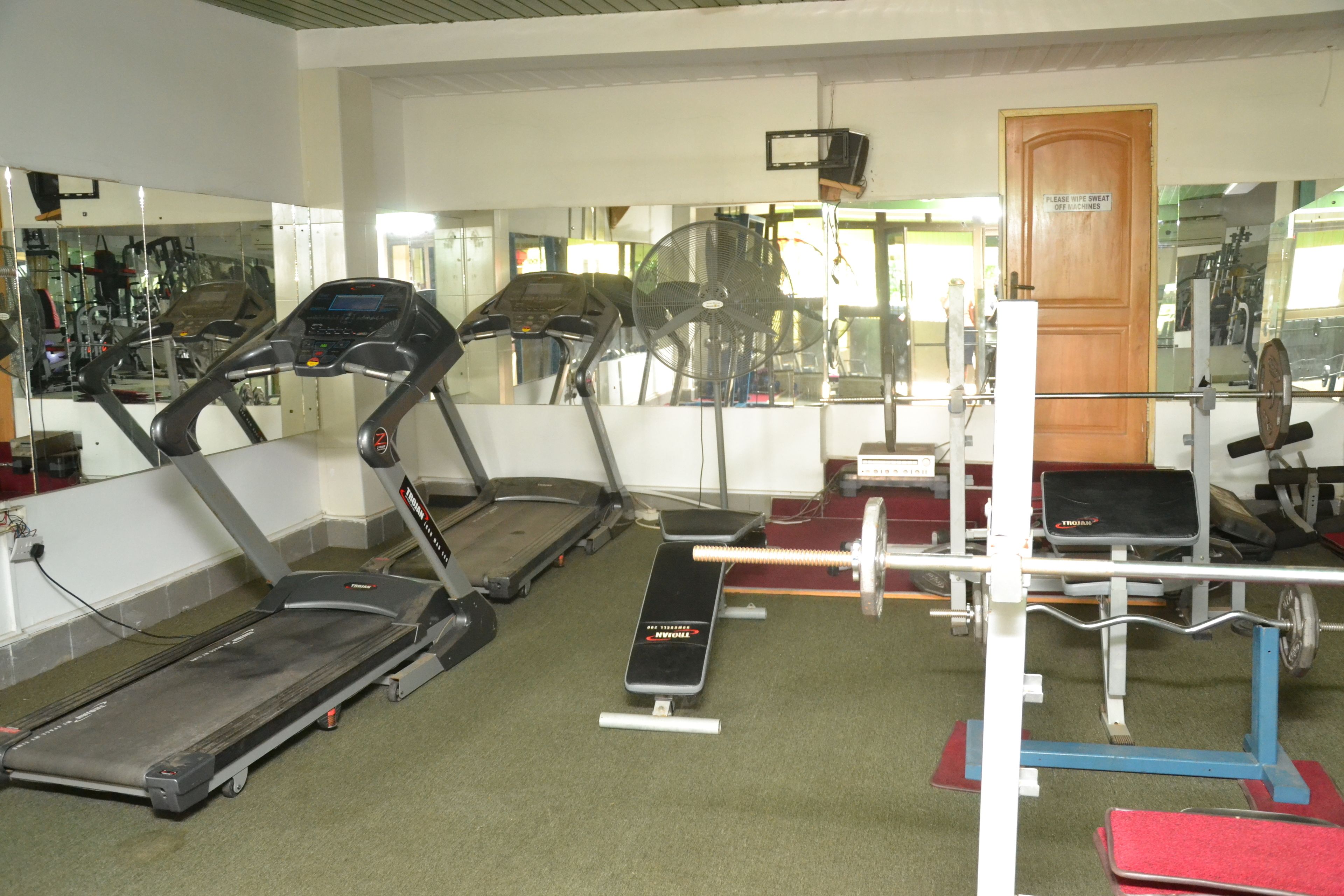 Un gimnasio con cintas de correr, una prensa de banca y un soporte para pesas.