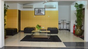 A lobby with a glass coffee table, two black leather sofas, a framed picture on the wall, and a potted plant. - Kaysens Grande Hotel (Tema)