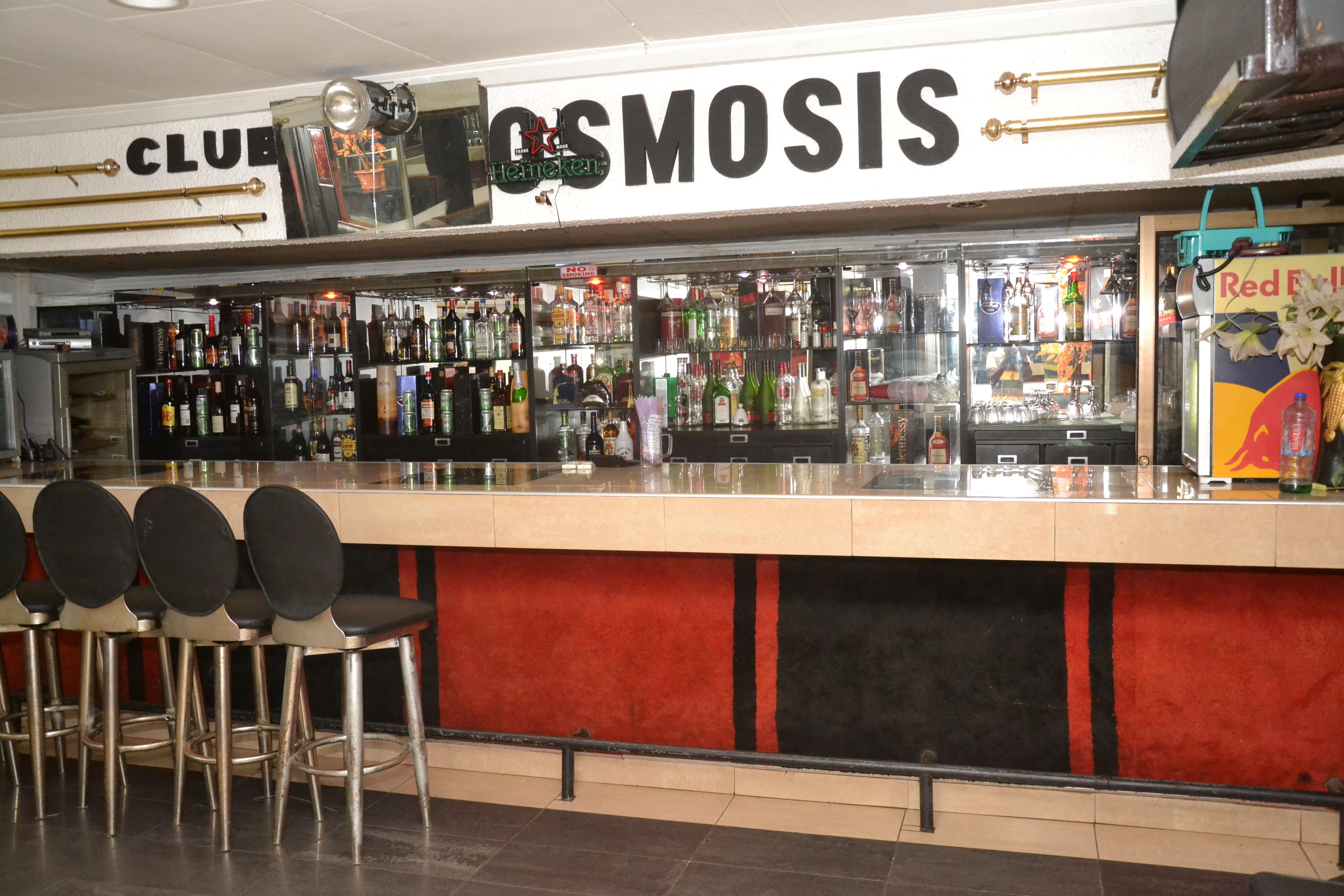 Eine Bar mit einer Theke, Hockern und einer Auswahl an Flaschen und Gläsern.
