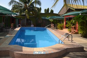 Una piscina al aire libre, sombrillas, sillones reclinables de piscina