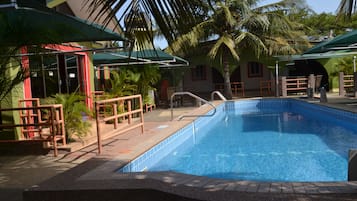 Una piscina al aire libre, sombrillas, sillones reclinables de piscina