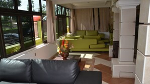 A modern living room with a grey sofa, a green sofa, and a fireplace. - Kaysens Grande Hotel (Tema)