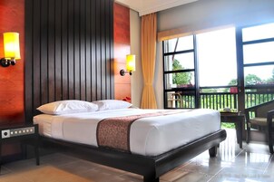 Habitación de hotel con cama, dos lámparas de pared, ventana con vista a zonas verdes y balcón con una silla.