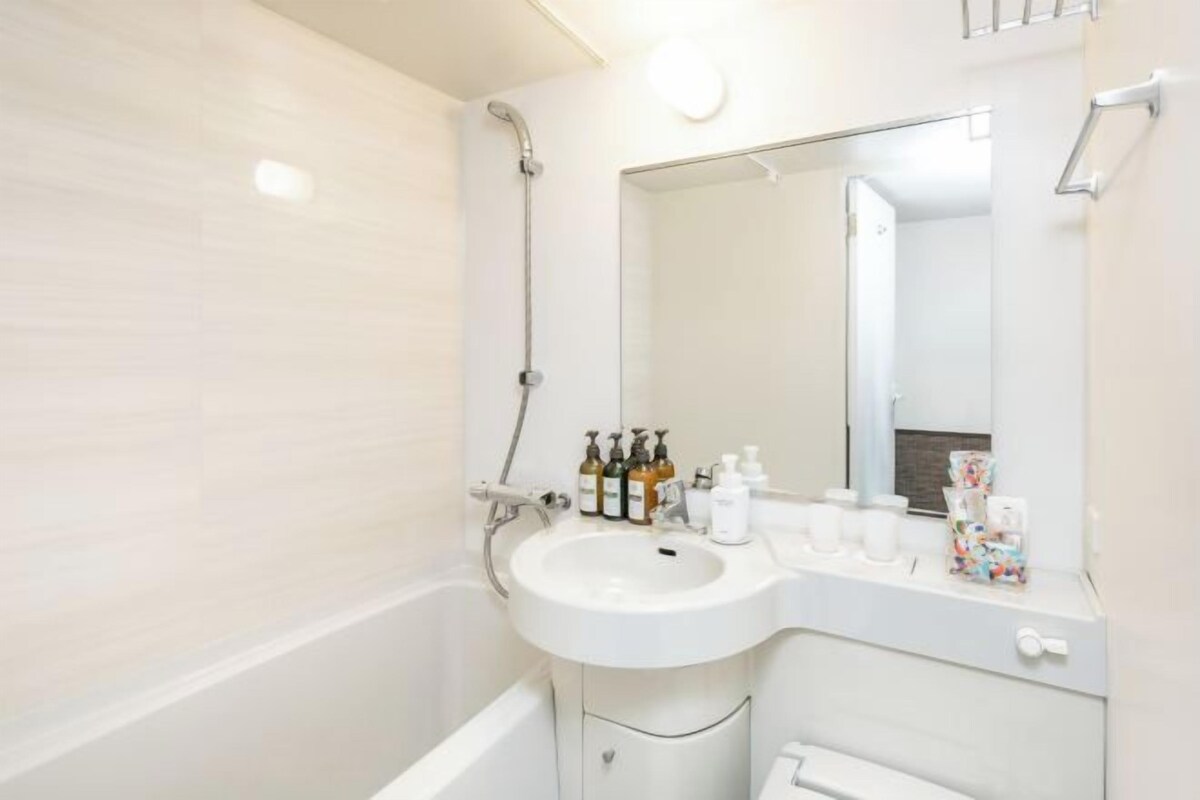 A bathroom with a white sink, a mirror, and toiletries on the counter.