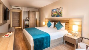 A hotel room with a bed, bedside table, lamp, and a refrigerator.