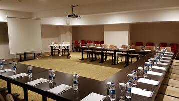 A conference room with a long table, chairs, water bottles, and a projector screen.