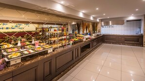 A buffet area with various food items and a kitchen in the background.