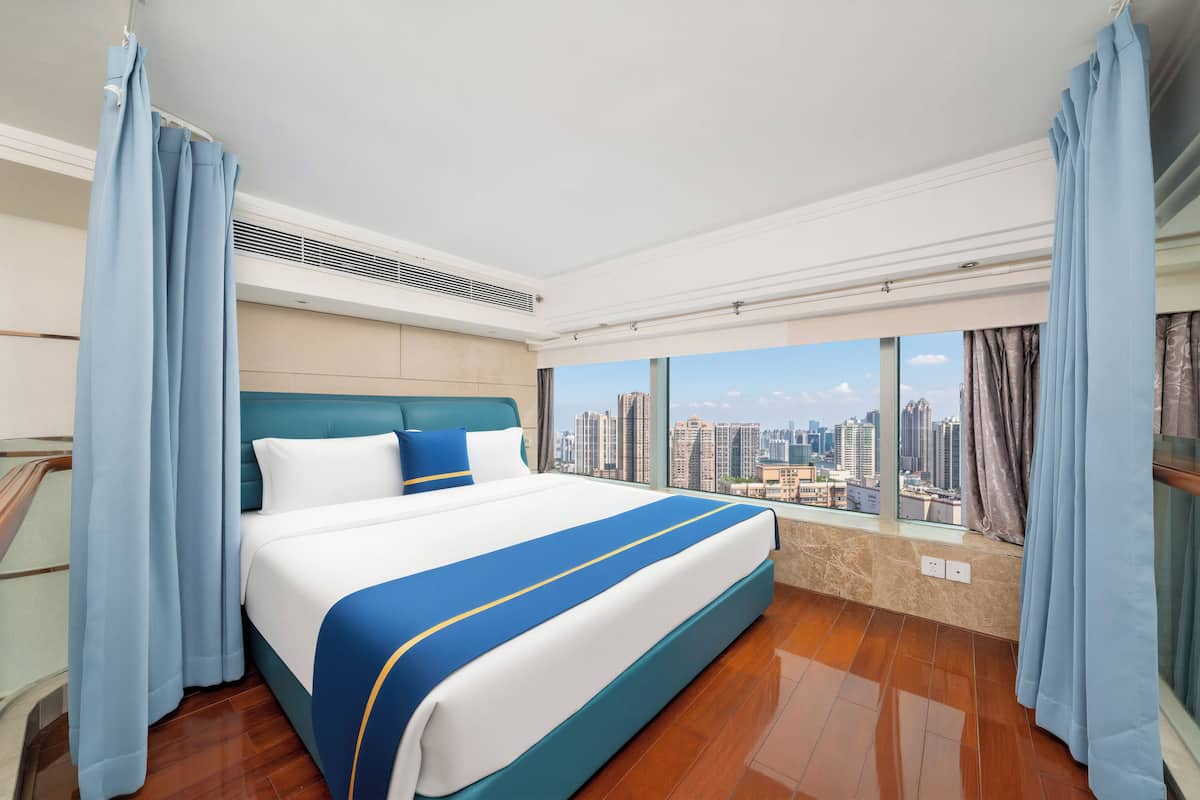 A hotel room with a large bed, a city view, and a balcony.