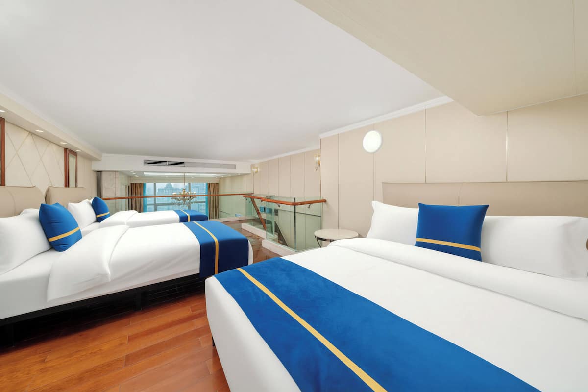 A hotel room with two beds, a balcony, and a view of the city.