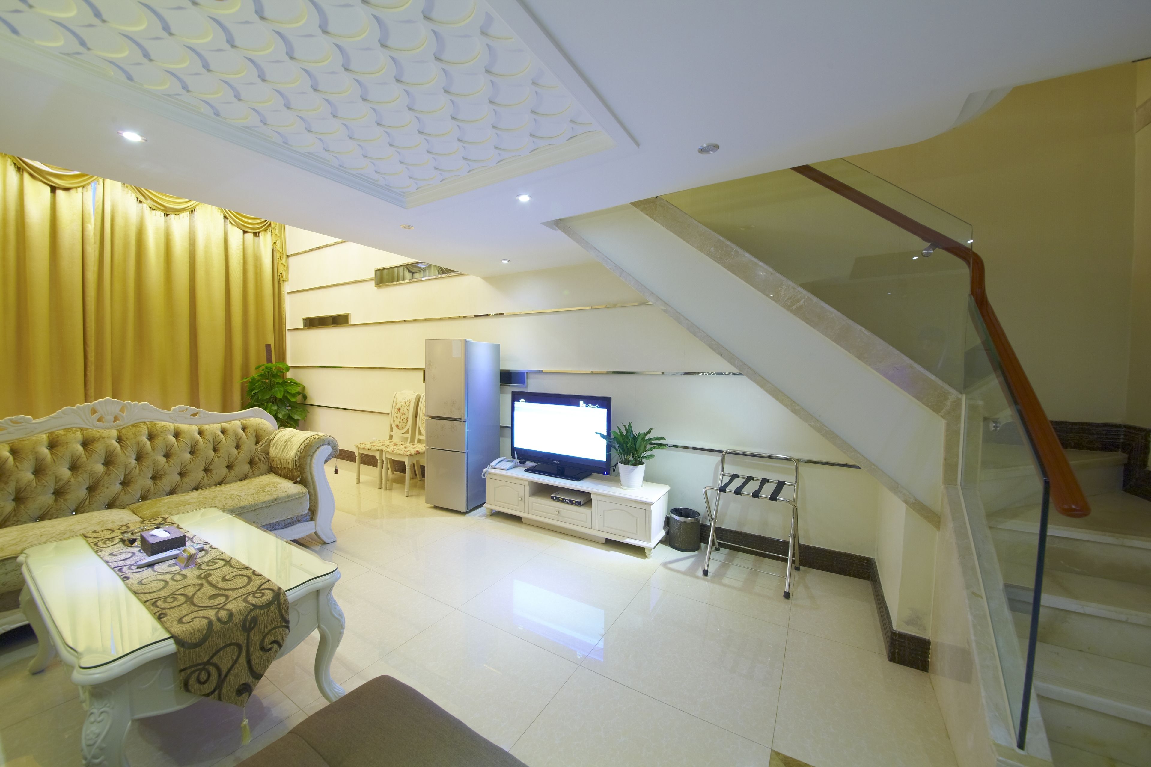 A modern living room with a sofa, coffee table, TV, and a staircase.