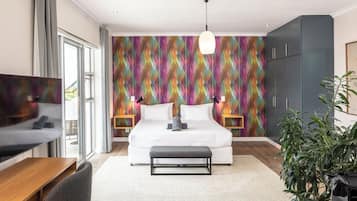 A modern bedroom with a large bed, bedside lamps, a TV, and a desk.