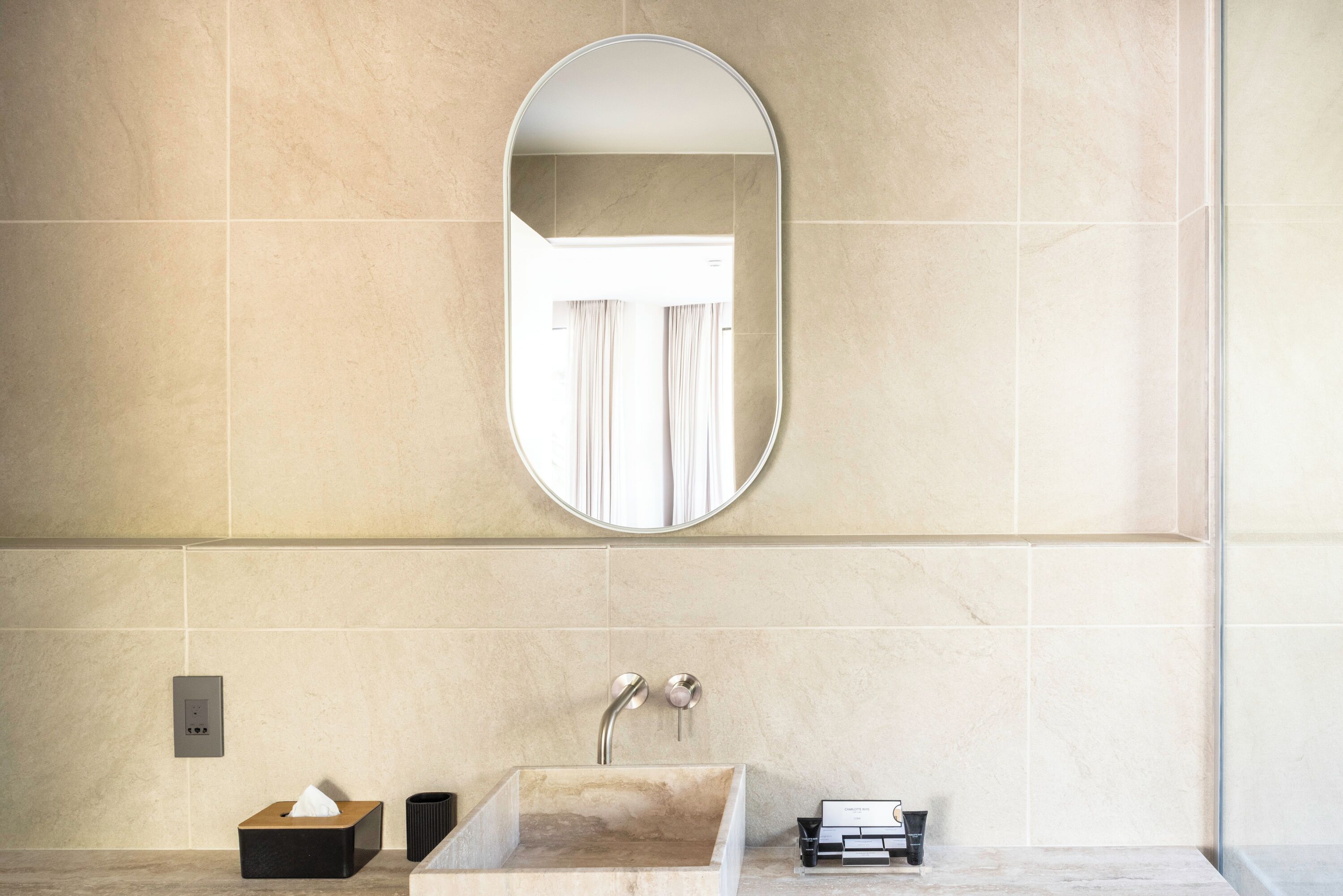 A bathroom with a marble sink, a mirror, a towel dispenser, and a tissue box.