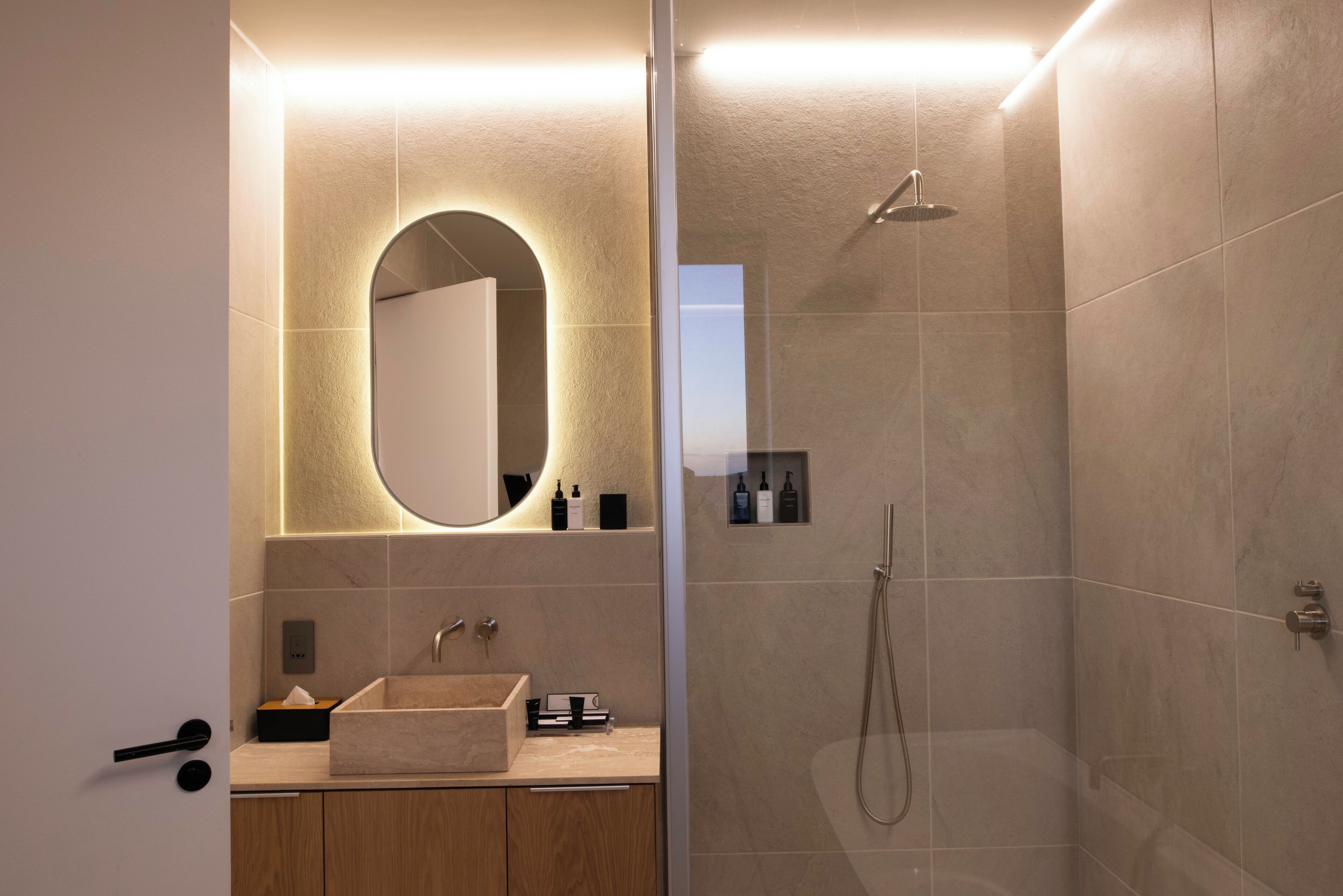 Un baño moderno con un espejo grande, un lavabo y una ducha.
