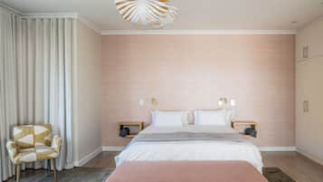 Un dormitorio moderno con una cama grande, mesitas de noche, un banco, una silla y una lámpara de techo original.