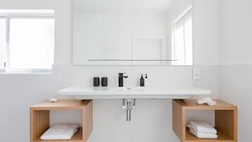 Une salle de bain moderne avec un lavabo blanc, un robinet noir et deux porte-serviettes en bois.