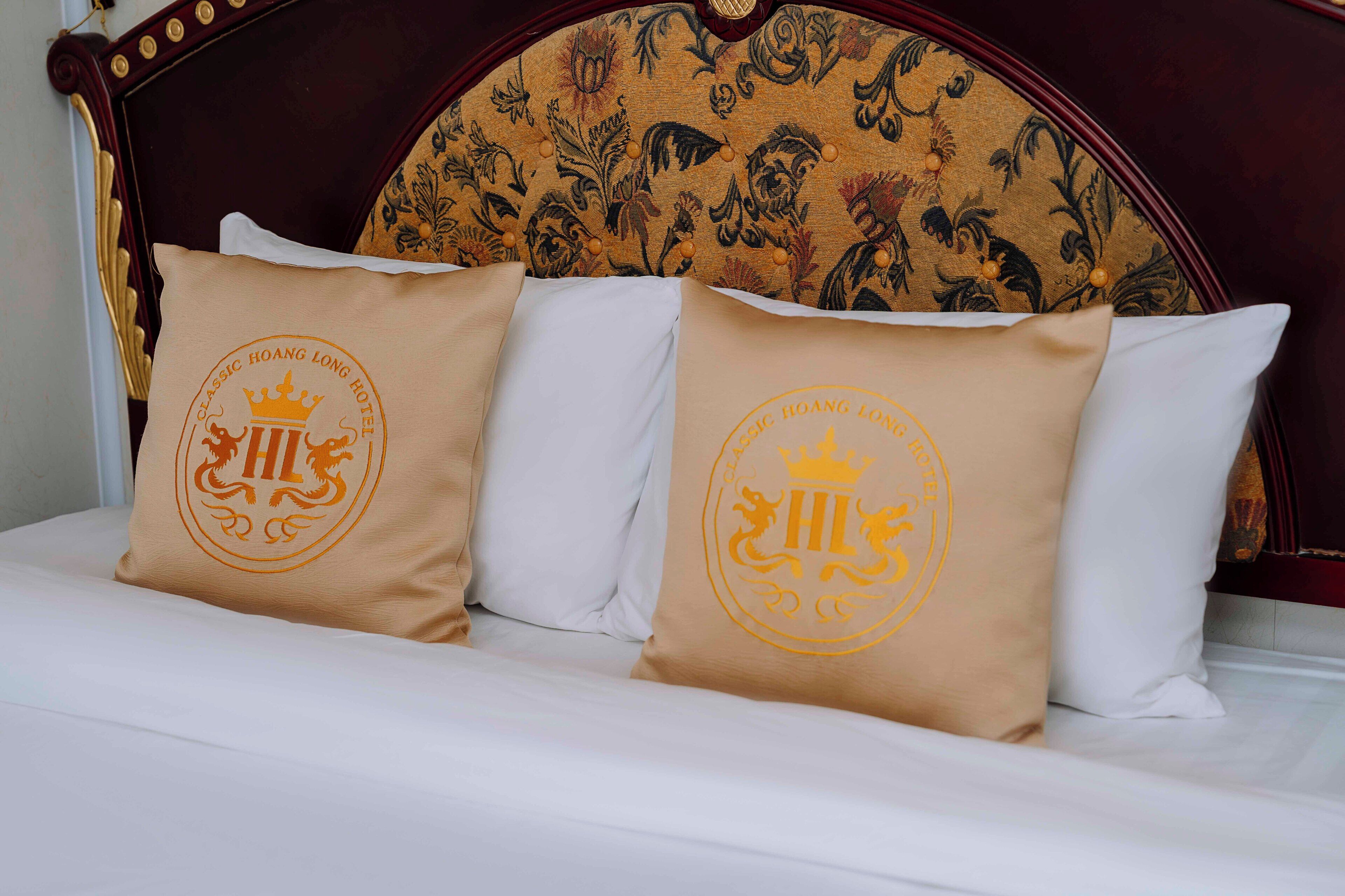Una cama con dos almohadas que muestra el logotipo de un hotel.