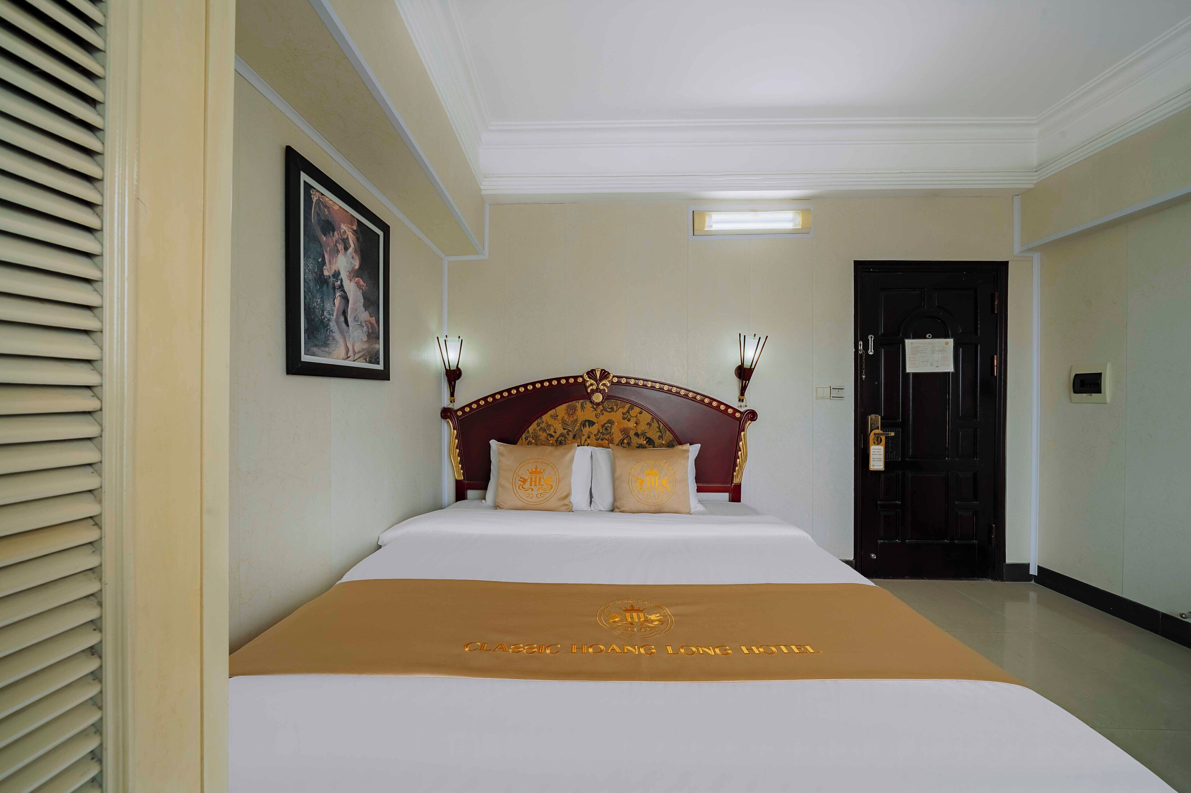 A hotel room with a large bed, a framed picture on the wall, and a door with a sign.