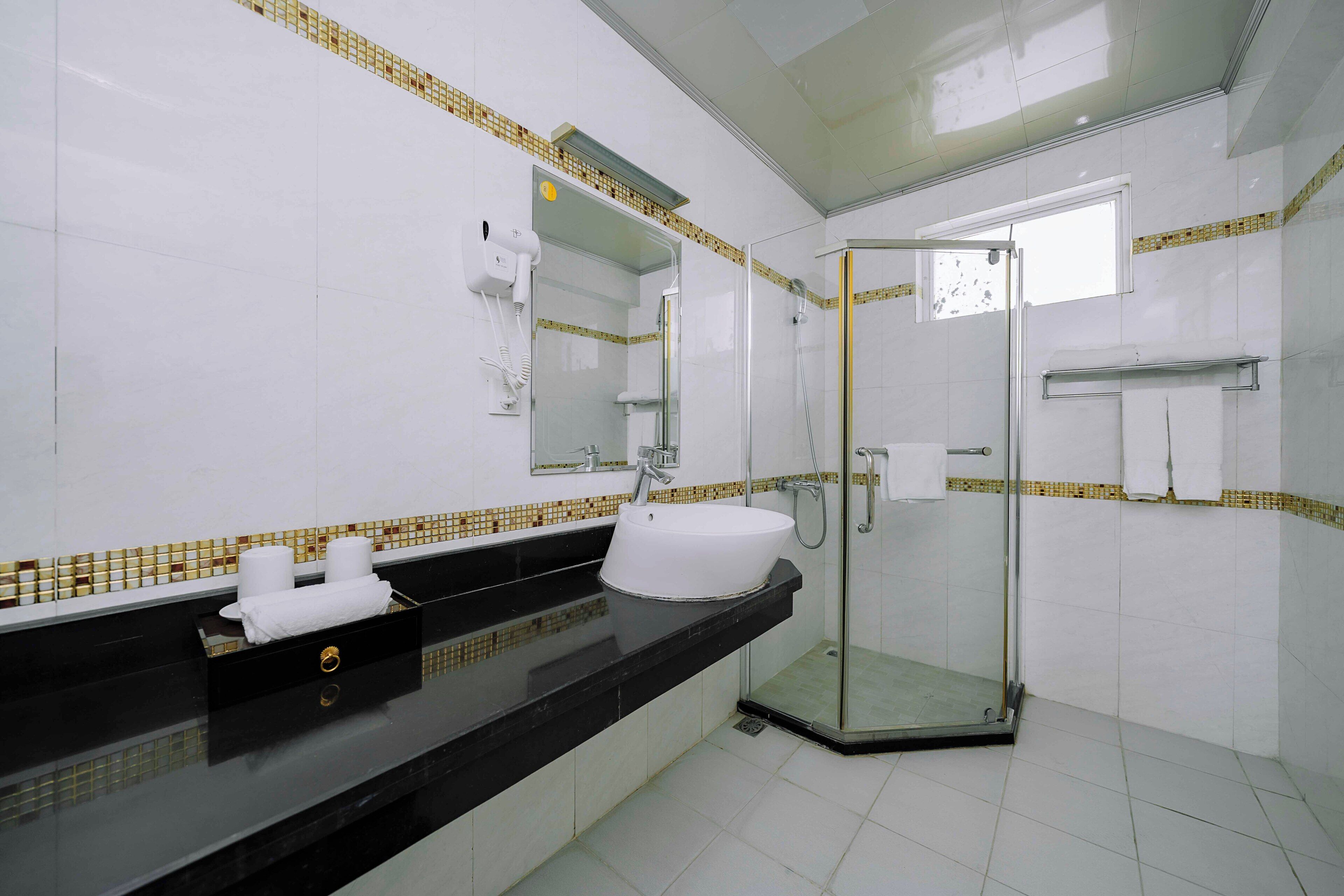 A modern bathroom with a black countertop, white sink, and a glass shower enclosure.