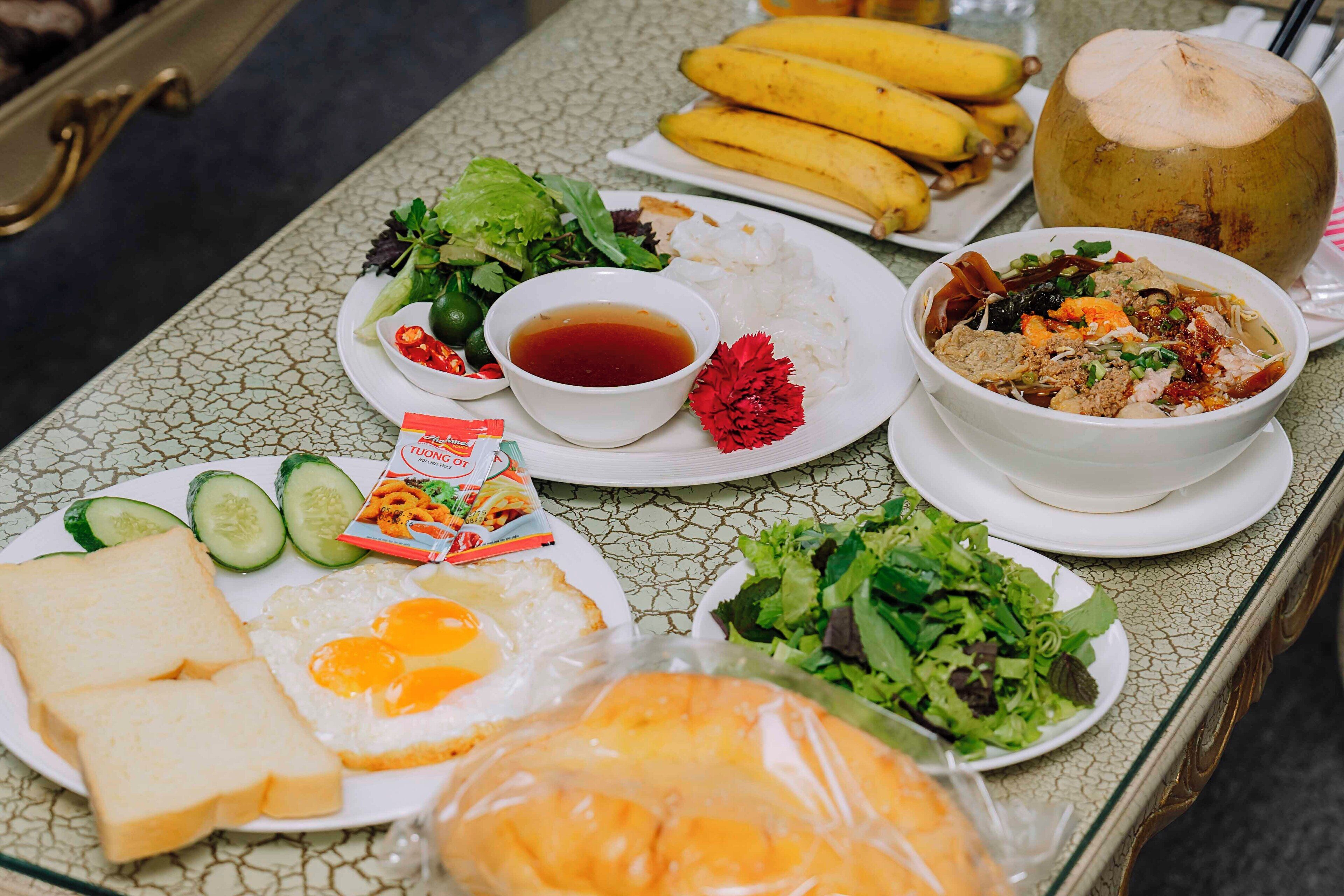 Una mesa con diversos alimentos, como huevos, pan, una ensalada y un tazón de sopa.
