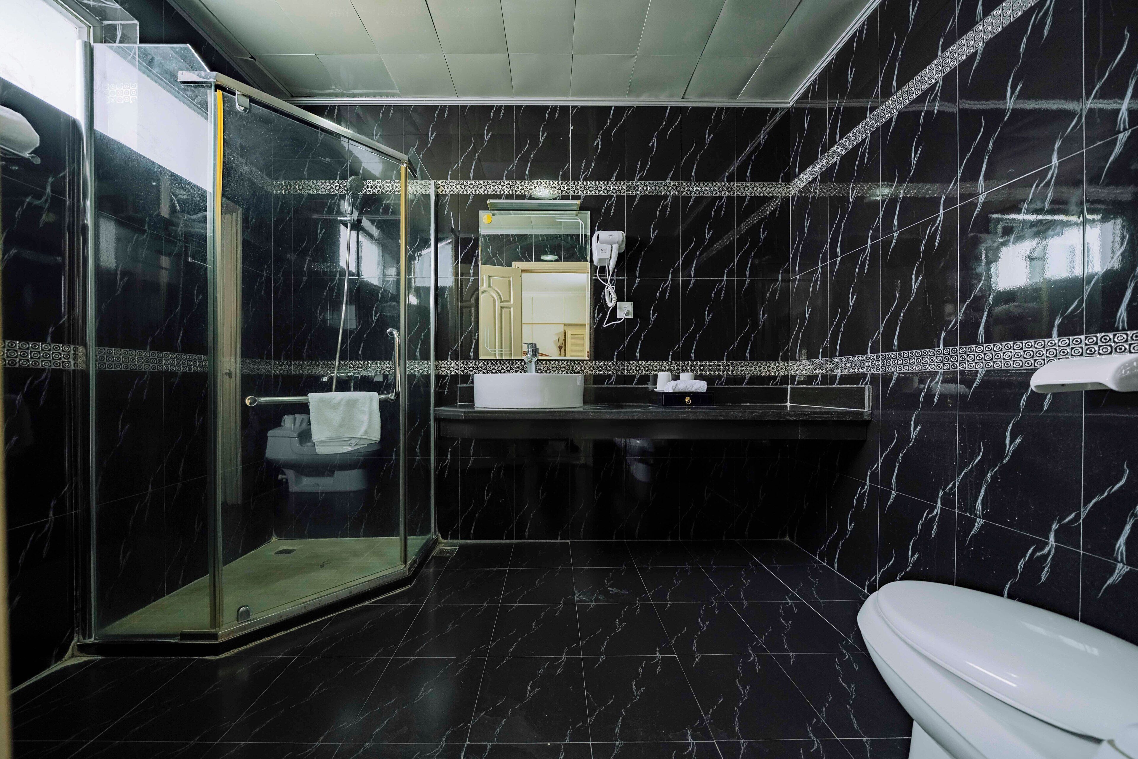 A modern bathroom with a glass-enclosed shower, a white toilet, and a sink with a mirror above.