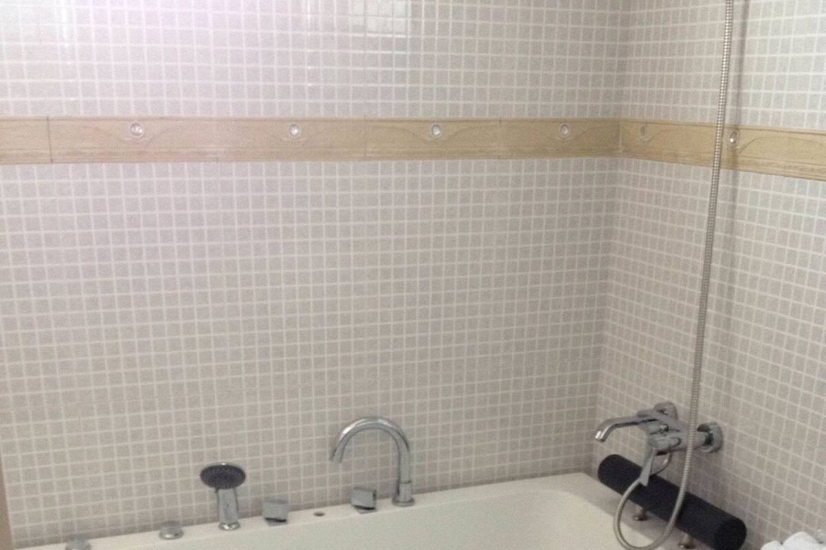 A bathroom with a white bathtub, a shower, and a black countertop.