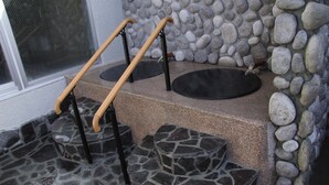 Una escalera de piedra con barandilla y un muro de piedra con diseño de guijarros.