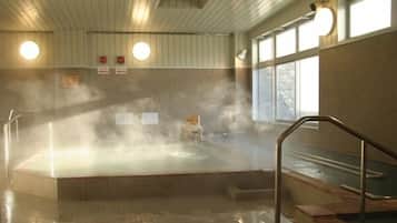 A steam room with a hot tub, tiled floor, and wooden walls.