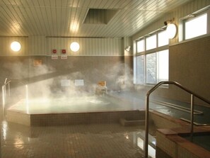 A steam room with a hot tub, tiled floor, and wooden walls. - Hidamarinoyu Flop House - Hostel (Takayama)