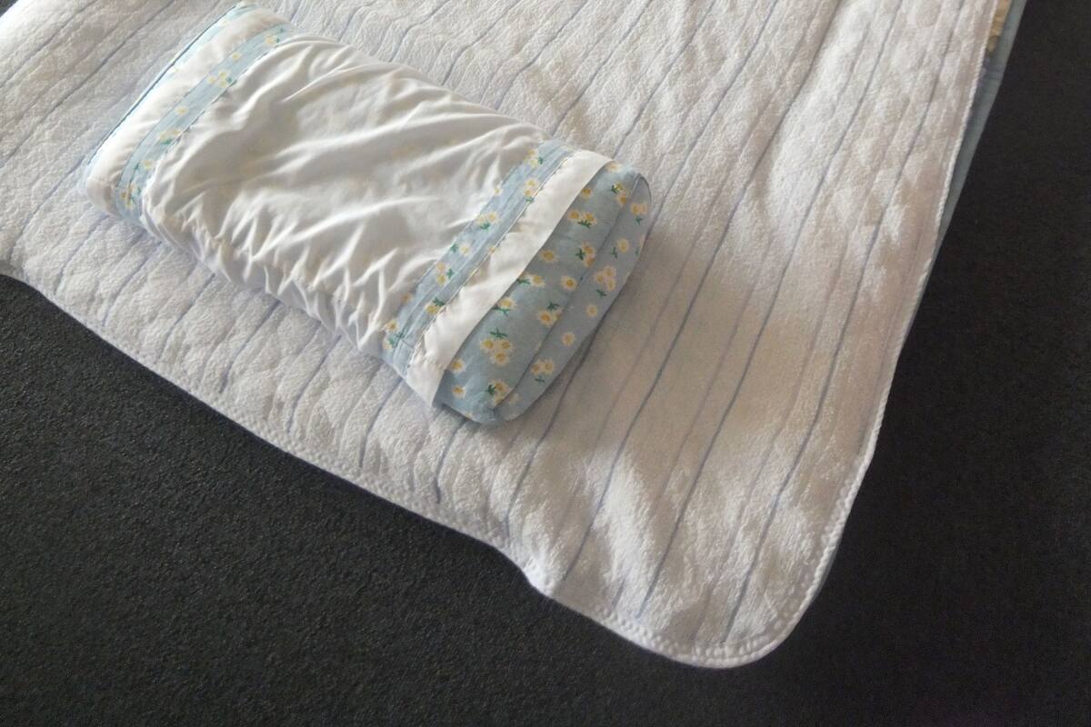 A neatly made bed with a striped bedspread and a pillow with a floral pattern.