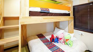 Habitación con literas de madera, una colcha estampada y peluches en la cama inferior.