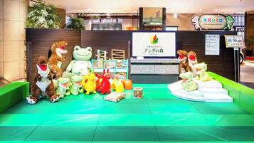 Zona de recepción con peluches, un cartel y un área de asientos con cojines verdes.