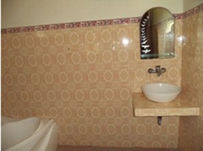 A bathroom with patterned tiles, a sink, and a mirror.