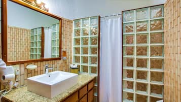 Un baño con un espejo grande, un lavamanos y una cortina de ducha.