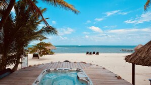 A wooden deck with a hot tub, palm trees, beach chairs, and a thatched umbrella. - Xanadu Island Resort (San Pedro)