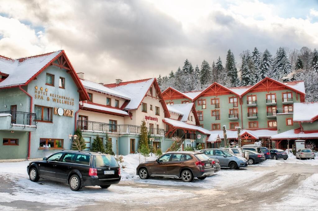 Ein Hotel mit mehreren Gebäuden, jedes mit rotem Dach und Balkonen. Vorne sind mehrere Autos geparkt.