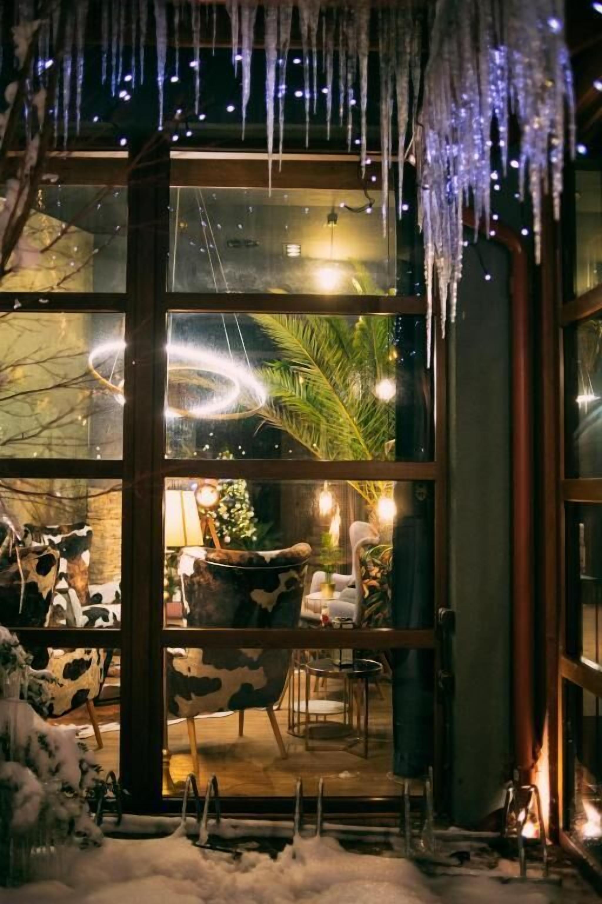 A cozy interior with a glass door leading to a seating area, a Christmas tree, and a fireplace.