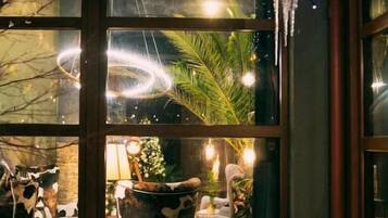 A cozy interior with a glass door leading to a seating area, a Christmas tree, and a fireplace.