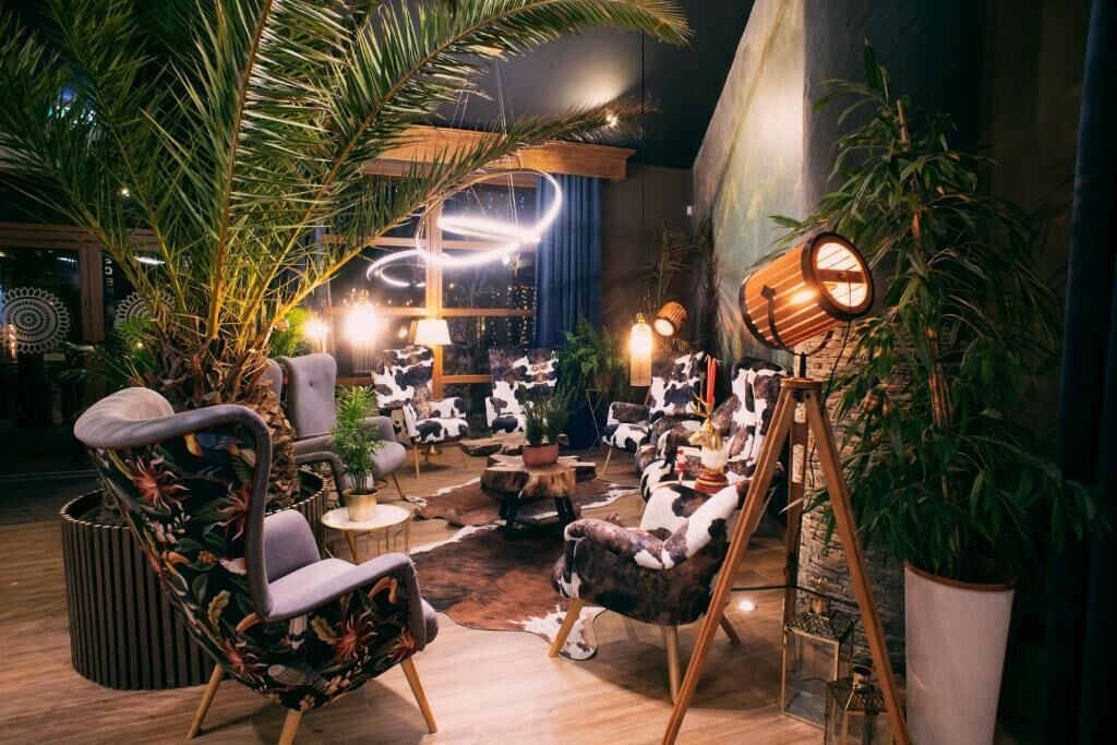 Un área de descanso con asientos, plantas e iluminación decorativa.