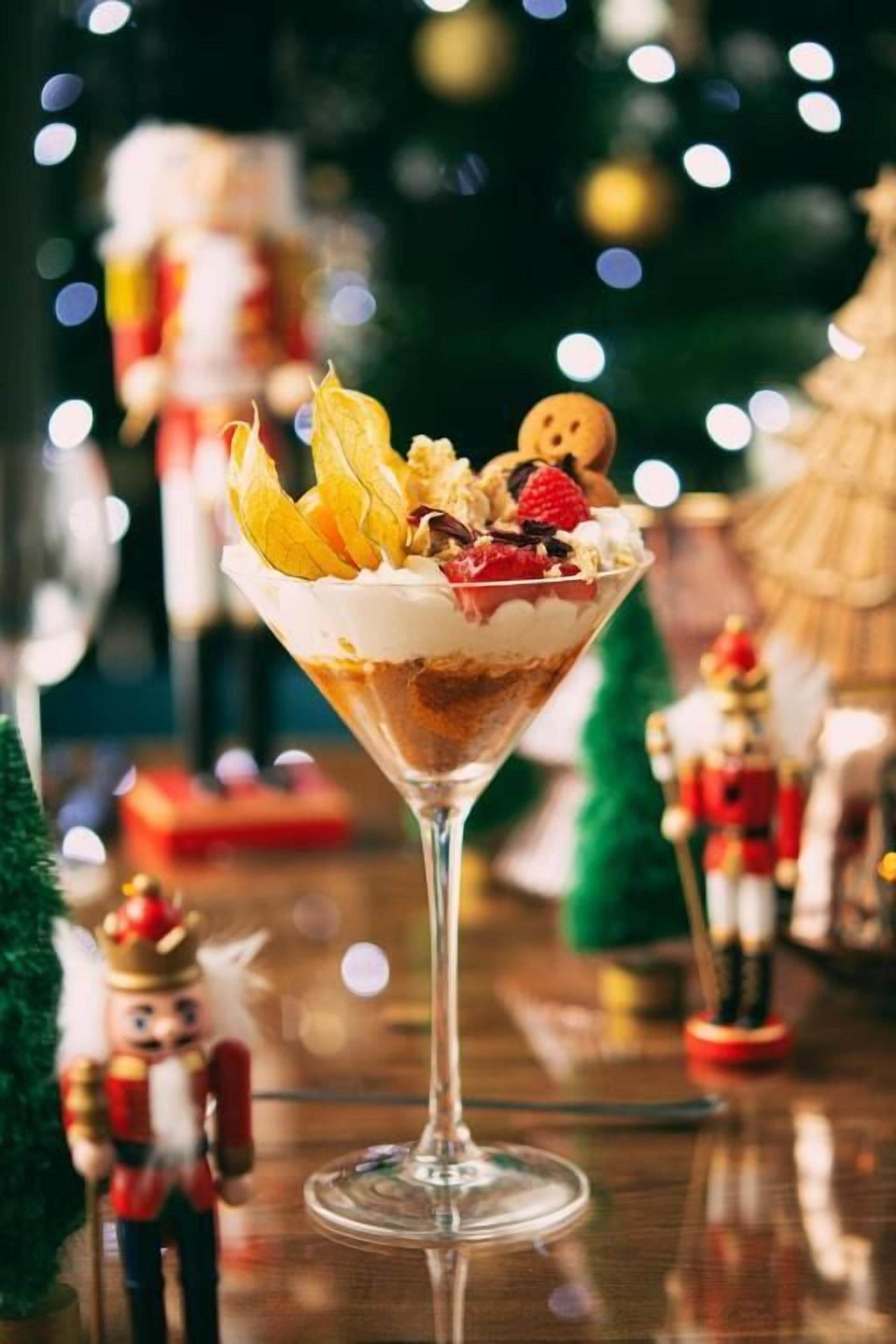 Un postre en vaso con crema batida, fruta y trozos de galleta.
